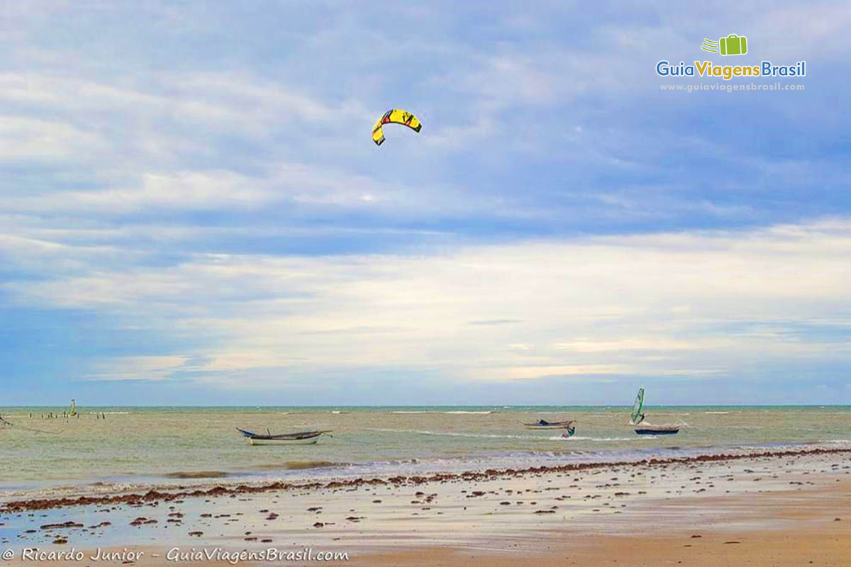 Imagem de barcos no mar e pessoas praticando esporte kitesurfe e windsurfe, na Praia  Icaraí de Amontada.